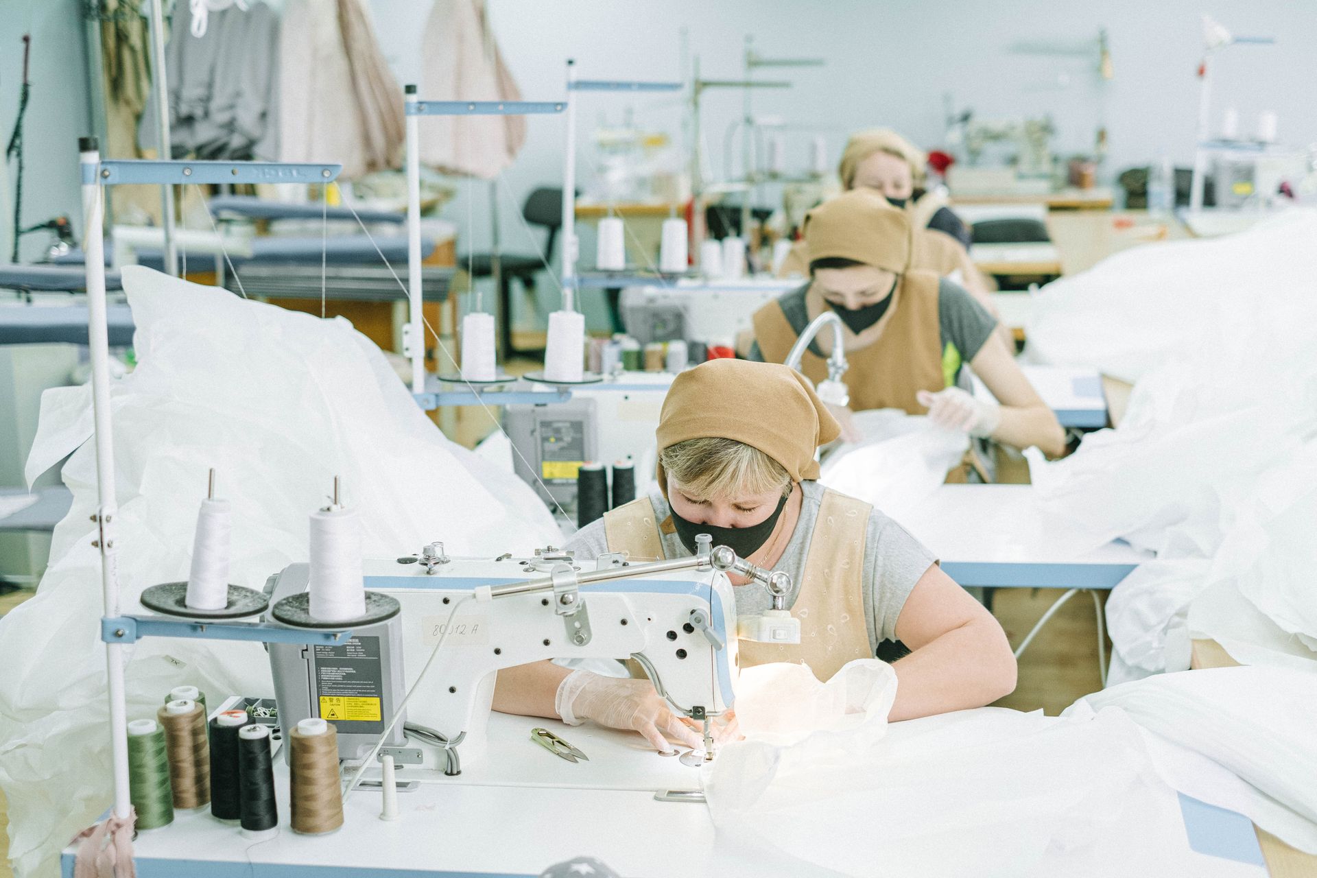 Sewing team assembling garments at workstations in a bright production studio