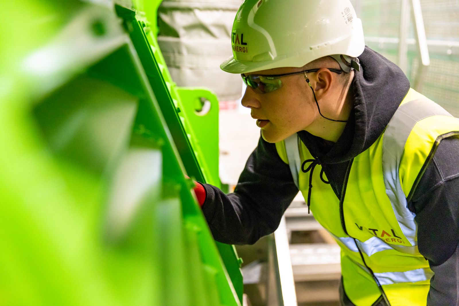 Factory worker wearing a safety helmet and high-visibility vest inside a plant