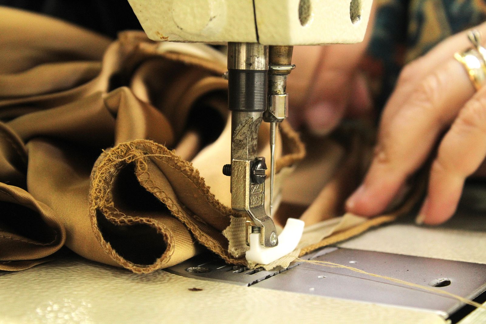 Close-up of hands guiding fabric through an industrial sewing machine