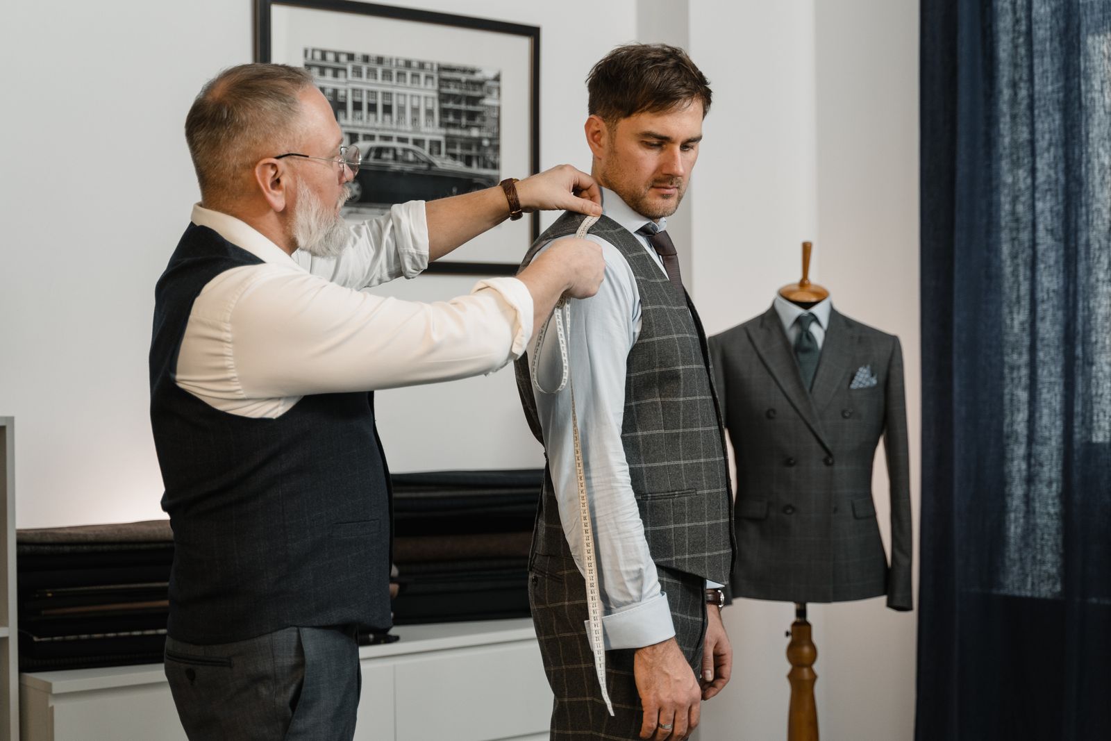 Tailor measuring a client with a tape measure for a custom garment