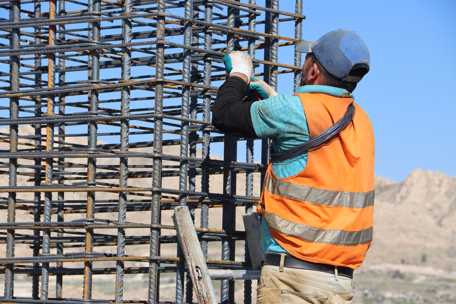 Worker in a high-visibility safety vest and cap on an outdoor construction site